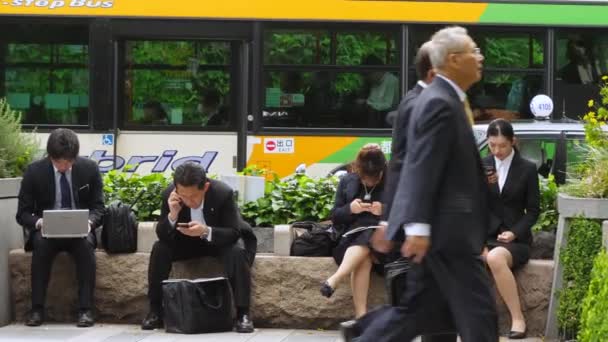 Men and women sitting on the side of the streets in Tokyo Japan — Stockvideo