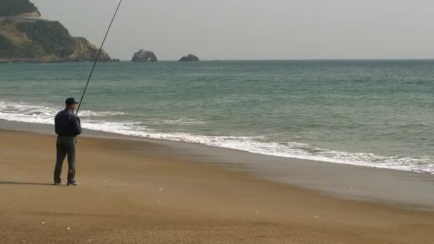 En man som rullar sitt fiskespö i Koijigahama Beach i Tahara Japan — Stockvideo