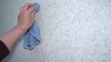Bir bayanın eli mavi kumaşla sağa sola hareket ediyor.