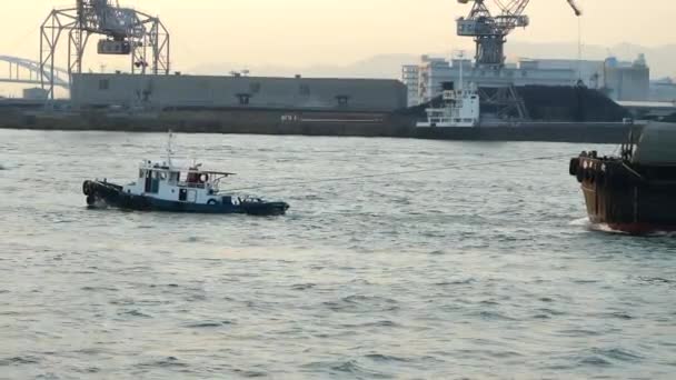Ένα μικρό σκάφος που τραβά το μεγάλο επιβατηγό πλοίο στο λιμάνι της Οσάκα στην Ιαπωνία — Αρχείο Βίντεο