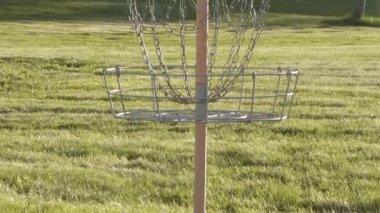 Arka planda karavan parkı olan bir disk golf sepetinin yakın çekimi..
