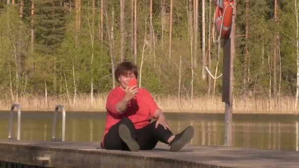 Közelebb egy középkorú hölgyről, aki szelfiket készít egy úszó hídon.. — Stock videók