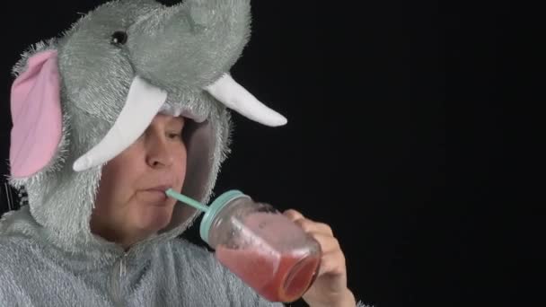 Et nærbilde av en dame i elefantdrakt som drikker smoothie. – stockvideo