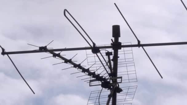 Arka planda bulutlu gökyüzü olan bir çatıdaki antenlerin yakın plan görüntüsü. — Stok video