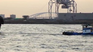 A small boat pulling out the big vessel on the back in Osaka Japan