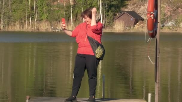 Bliższe ujęcie kobiety robiącej selfie na pływającym moście. — Wideo stockowe