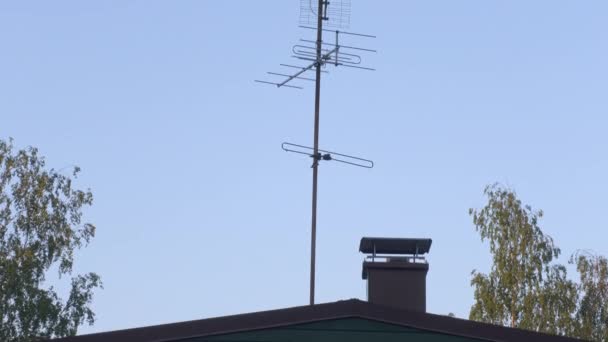 Szép kis antennák a tetőn tiszta égbolttal és fákkal a háttérben.. — Stock videók