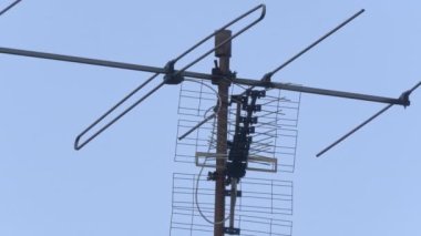 Arka planda mavi gökyüzü olan bir çatıdaki antenlerin yakın plan görüntüsü.