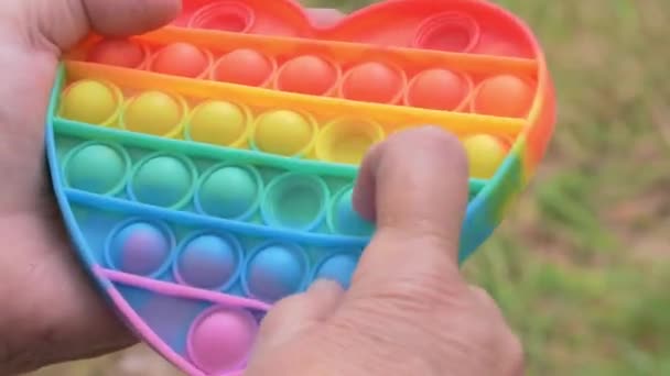Gros plan de quelqu'un jouant avec un jouet pop it coloré. — Video