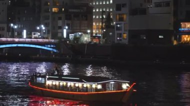 Tokyo 'da gece vakti nehirde seyreden teknenin görüntüsü.