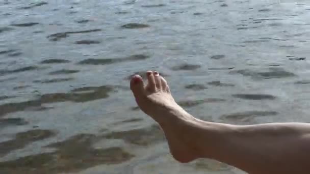 Närbild skott av en kaukasiska kvinnors ben med vatten i bakgrunden. — Stockvideo