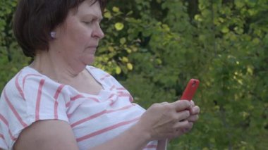 Orta yaşlı bir kadının cep telefonunu kullanırken güzel bir fotoğrafı..