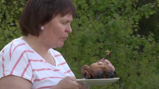 Дивовижний знімок леді середнього віку, що їсть курку на грилі . — стокове відео