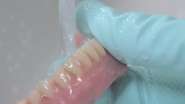 Primer plano mostrando la limpieza de los dientes artificiales bajo el agua corriente. — Vídeo de stock