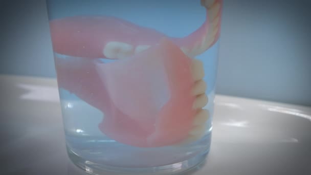 Close-up shot van kunstgebit in een glas terwijl het glas beweegt. — Stockvideo