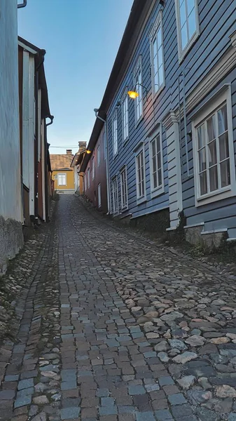 Porvoo, Finlandiya - 08 Aralık 2020: Cobblestone Caddesi sokak lambalarıyla aydınlatılmış renkli evlerle dolu, akşam ışığında büyüleyici bir atmosfer yaratıyor