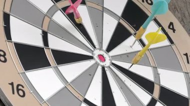 Dart tahtasına birkaç dart dartının yakın çekimi. İyi bir eğlence aktivitesi. Eğlenceli bir oyun ve aynı zamanda bir spor. Renkli oklar. Kamera yavaşça uzaklaşıyor.