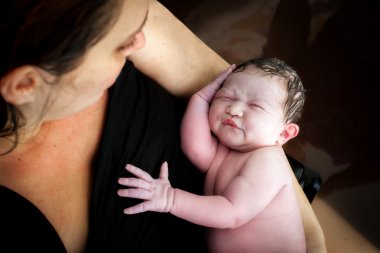 Bir anne yeni oğlu bir Birthing havuzunda tutar.