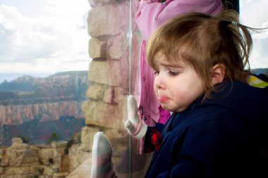 Crying Girl Looks out Window at Grand Canyon clipart