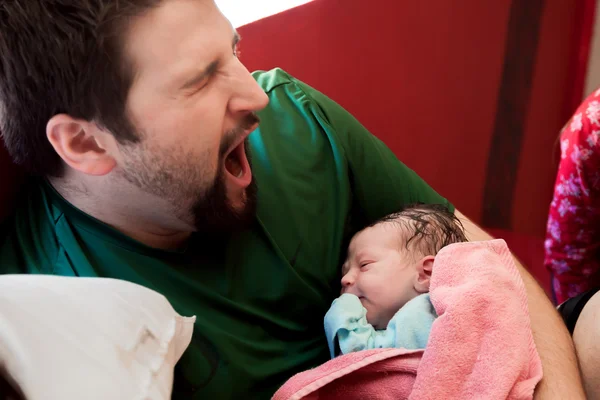 Yeni doğan oğlu tutarken baba Yawns