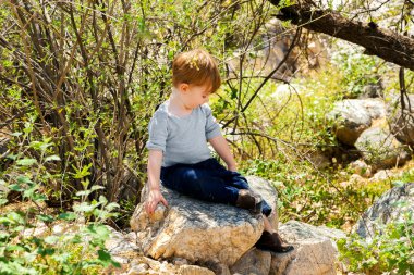 küçük çocuk bir taşa oturur 