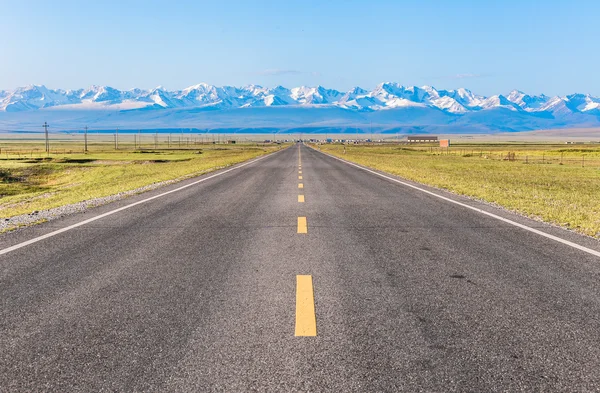 A straight road under the snow mountain.A straight road under the snow mountain.