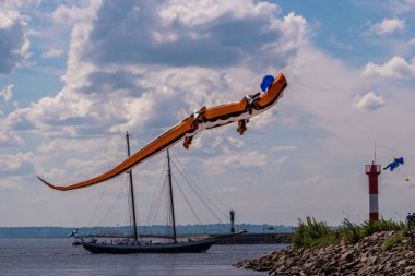 - Rusya. Kronstadt 'ta. 6 Haziran 2021. Kronstadt Yelken Festivali sırasında Konstantin Kalesi 'nden geçen bir yelkenli gemisinin arka planında kertenkele şeklinde uçan bir figür..