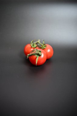 Basit, doğal bileşim kiraz domateslerinin parlak kırmızı rengini düz, koyu bir yüzeye karşı gösteriyor. Minimalist tasarımlar ve yemek blogları için ideal.