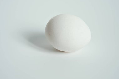 Parlak, temiz bir stüdyo ortamında beyaz bir tabakta duran iki beyaz yumurtanın yakın çekimi..