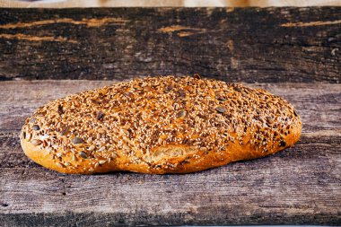 Koyu kepekli ekmek, eski ahşap masa üzerinde.