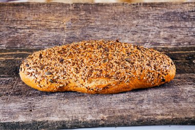 Kırsal arka planda çeşitli tohumlarla kaplı ekmek somunu.