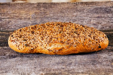 Koyu kepekli ekmek, eski ahşap masa üzerinde.