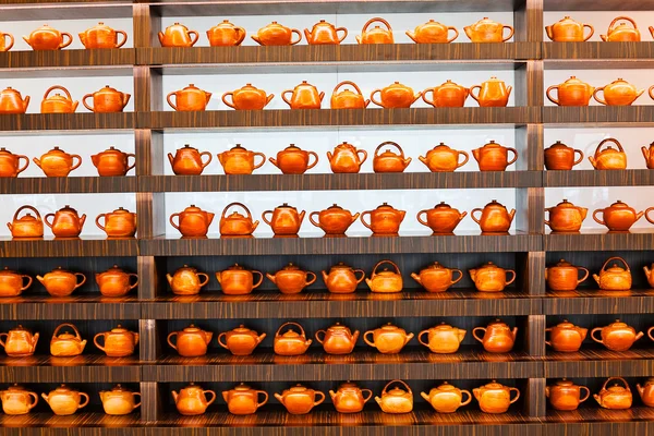 Mağazadaki raflarda çeşitli kil çaydanlıklar var.