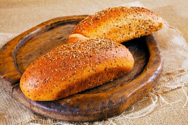 Üzerinde farklı tohumlar olan iki kahverengi baget, yuvarlak tahta üzerinde.