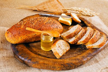 Bal, tereyağı ve dilimlenmiş siyah ekmek, yuvarlak tahta üzerinde.