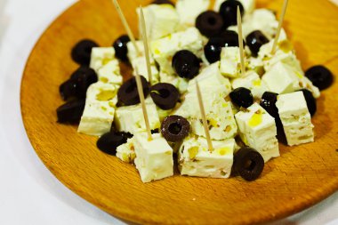 Ahşap tabakta siyah zeytinli keçi peyniri.