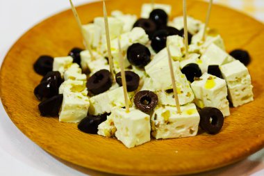 Ahşap tabakta siyah zeytinli keçi peyniri.