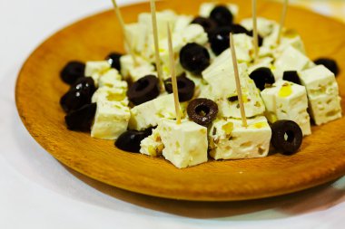 Ahşap tabakta siyah zeytinli keçi peyniri.