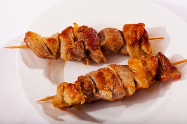 Beyaz arka planda, beyaz tabakta domuz şişi.