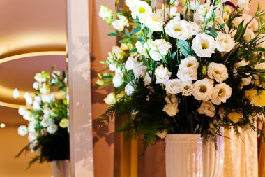 Gelinlik butiği içinde güzel bir buket beyaz çiçek, aynanın önünde.