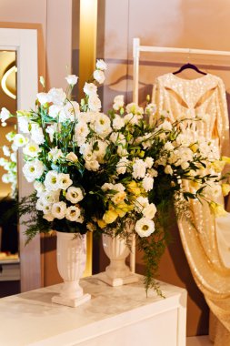 Gelinlik butiği dekorasyonu, beyaz buketler ve beyaz gelinlik.