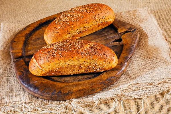 Zwei Braune Baguette Mit Verschiedenen Samen Auf Rundem Holzbrett — Stockfoto