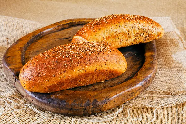 Zwei Braune Baguette Mit Verschiedenen Samen Auf Rundem Holzbrett — Stockfoto