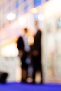 Blur of two men standing and talking; blurred 100%