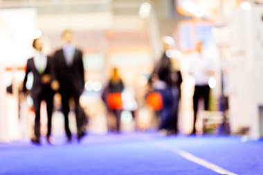 Two men looking at stands at job expo; blurred 100%