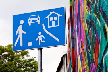 Arka planda gökyüzü ve duvar resmi olan mavi yerleşim yeri işareti