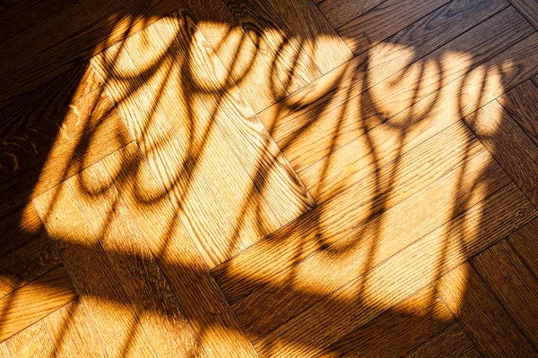 stock image Sunlight from window with iron fence, falling on wooden floor in dark room