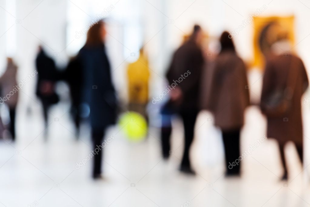 Group of people in art gallery watching paintings; blurred 100%