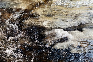 Kışın buzla kaplanmış, küçük bir derenin soğuk akan suyu.