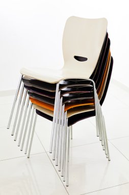 Beyaz odaya istiflenmiş plastik sandalyeler, yan görüş